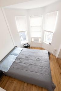 ein großes Bett in einem Zimmer mit drei Fenstern in der Unterkunft Deluxe Studio Apt Close to NYC in Union City