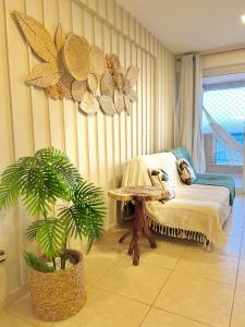 a room with a bed and a table and a plant at Apartamentos no Condomínio Beach Village Fortaleza - Praia do Futuro - Por CasAmarInn in Fortaleza