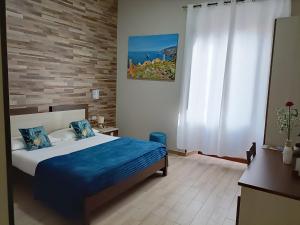 a bedroom with a bed with blue sheets and a brick wall at Domos La Corte Ghibellina in Iglesias