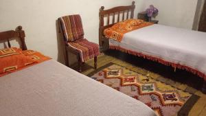 1 dormitorio con 2 camas, silla y alfombra en Hospedaje Los Balcones Jumbilla Bongará Amazonas, 