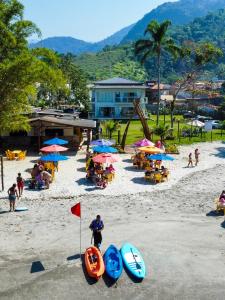 帕拉蒂的住宿－Pousada Cantinho da Praia，海滩上有人,沙滩上摆放着椅子和遮阳伞