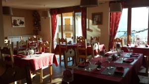 un comedor con mesas y sillas con mantel rojo en Hôtel Le Beauséjour, en Saint-François-Longchamp