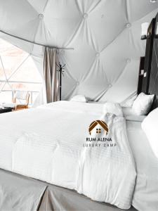 a bedroom with a white bed with a sign on it at RUM ALIENA LUXURY CAMP in Wadi Rum