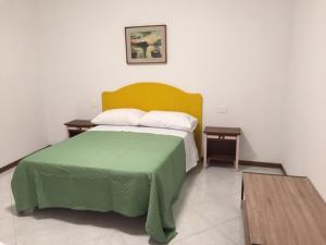 a bedroom with a green bed and two tables at Foresto Case Vacanza in Volta Mantovana