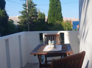 ein Holztisch und zwei Stühle auf einem Balkon in der Unterkunft Apartmani Sara Marija in Karlobag