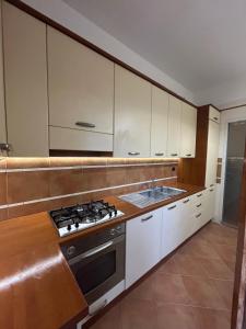 La cuisine est équipée de placards blancs et d'un four avec plaques de cuisson. dans l'établissement Lux apartment San Paolo, à Rome