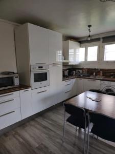 cocina con armarios blancos y mesa de madera en Charming Comfy Apartment in Amiens, en Amiens