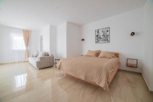 a white bedroom with a bed and a chair at White House Radac Peja in Peje