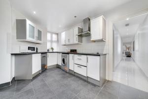 een keuken met witte kasten en een wasmachine en droger bij 2Bd Flat Opp Harrods - Sleeps 5 in Londen