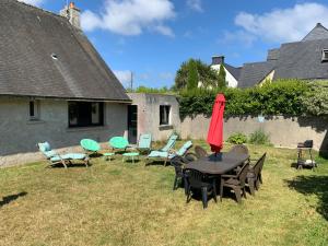 Saint-Quay-Perros的住宿－GRANIT COCOON，庭院配有桌椅和遮阳伞。
