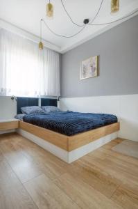 Schlafzimmer mit einem Bett mit blauer Decke in der Unterkunft Golden Apartments Łodz&G147A in Łódź