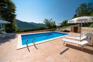 a swimming pool with two chairs and an umbrella at Casetta in Pietra in Acqualagna