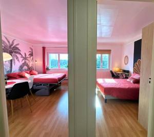 een roze kamer met 2 bedden en een tafel bij La Vue sur la Digue in Verdun-sur-Meuse