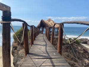 a wooden bridge over a beach with the ocean at Hotel Gambusino in Lázaro Cárdenas