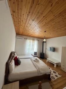 a bedroom with a large bed with a wooden ceiling at VILA DISHA in Tirana