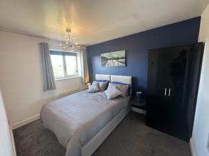 特倫特河畔斯托克的住宿－3 Bed Home for Contractors & Relocators with Parking, Garden & WiFi 30 mins to Alton Towers，一间卧室配有一张蓝色墙壁的床和一扇窗户