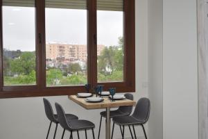 una mesa y sillas en una habitación con ventanas en FIBES Lux Sevilla Este., en Sevilla