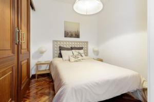 a bedroom with a bed with white sheets and a chandelier at Apartamento con ascensor, dos habitaciones in A Coruña