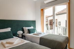 1 Schlafzimmer mit 2 Betten und einem Fenster mit Balkon in der Unterkunft City Hall Apartments in Vila Real