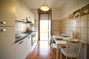 cocina con armarios blancos, mesa y sillas en Roman Holidays all'Eur, en Roma