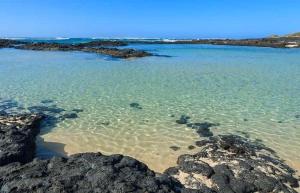 Una vista de una playa con rocas en el agua. en Lido Playa Apartamento, en Cotillo 4 fotos más