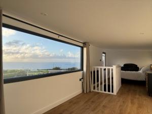 um quarto com uma grande janela com vista para o oceano em Lulla Lodge em Lower Boscaswell