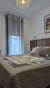 Una cama con una manta y una ventana en AMIZADE APARTAMENTO, en Pontevedra