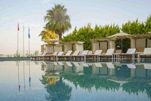 einen Pool mit Stühlen und Sonnenschirmen neben dem Wasser in der Unterkunft Qinn Hotel in Antalya
