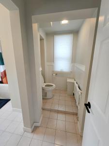 a white bathroom with a toilet and a window at Ottawa Downtown Cozy Guesthouse in Ottawa