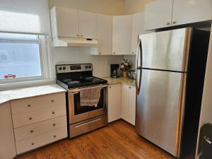 a kitchen with a stainless steel refrigerator and white cabinets at Ottawa Downtown Cozy Guesthouse in Ottawa