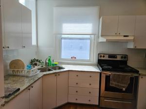 a kitchen with white cabinets and a sink and a window at Ottawa Downtown Cozy Guesthouse in Ottawa