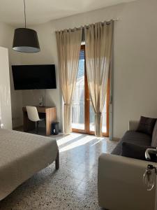 a bedroom with a bed and a couch and a tv at Mari & Monti Affittacamere in Sapri