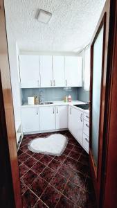 cocina con armarios blancos y suelo de baldosa roja en Apartment Sekulic, en Doboj