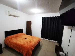 a bedroom with a bed with an orange blanket at Dream Lagoon, 15 min Aeropuerto in Monterrey