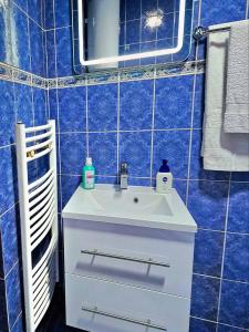 W wyłożonej niebieskimi kafelkami łazience znajduje się umywalka i lustro. w obiekcie Apartment Sekulic w mieście Doboj
