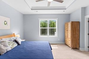 a bedroom with a blue bed and a window at Live Oak Villa~OKI Beach Retreat in Oak Island