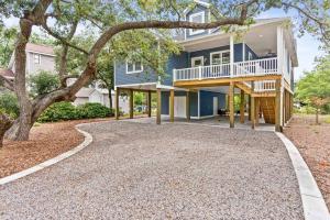 a large blue house with a tree and a driveway at Live Oak Villa~OKI Beach Retreat in Oak Island