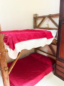 2 Etagenbetten in einem Zimmer mit roten Decken in der Unterkunft Green House saqua in Saquarema