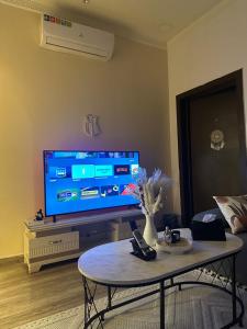 uma sala de estar com uma televisão grande e uma mesa de centro em شقة ب الحمراء بدخول ذاتي em Riyadh