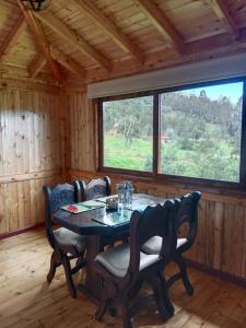 ein Esszimmer mit einem Tisch, Stühlen und einem Fenster in der Unterkunft Cabaña Colibri in Paipa