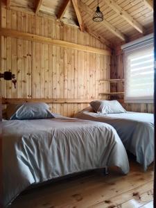2 łóżka w pokoju z drewnianymi ścianami w obiekcie Cabaña Colibri w mieście Paipa