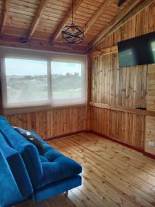 sala de estar con sofá azul y TV en Cabaña Colibri, en Paipa