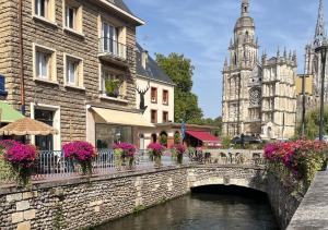 a bridge over a river in a city with a church at Le Charme D'Antan in Évreux
