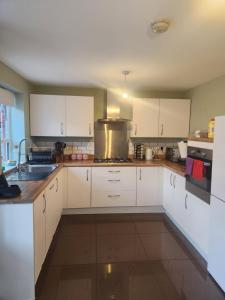 a kitchen with white cabinets and a stove top oven at Glamshouse in Bushbury