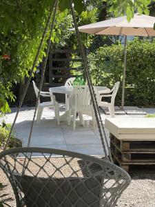 a swing with chairs and a table and an umbrella at Casa Sivori sul lago di Garda con ampio giardino in Desenzano del Garda