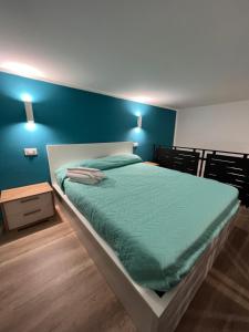 een slaapkamer met een groot bed met een blauwe muur bij Da Lello: Luxury Loft strategico in Marigliano