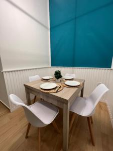 einem Holztisch mit weißen Stühlen und einer blauen Wand in der Unterkunft Da Lello: Luxury Loft strategico in Marigliano