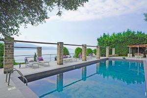 een zwembad met ligstoelen naast het water bij Villa Rachele: stunning luxury villa in centre Gargnano with private pool and breathtaking views in Gargnano