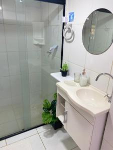 a bathroom with a sink and a shower with a mirror at Apto "Cantinho da Paula" in Maragogi