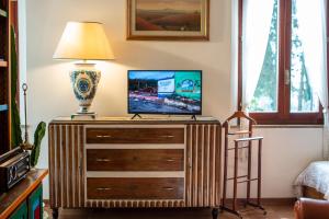 a tv on top of a wooden dresser with a lamp at Villa Elvira 1931 in Siena